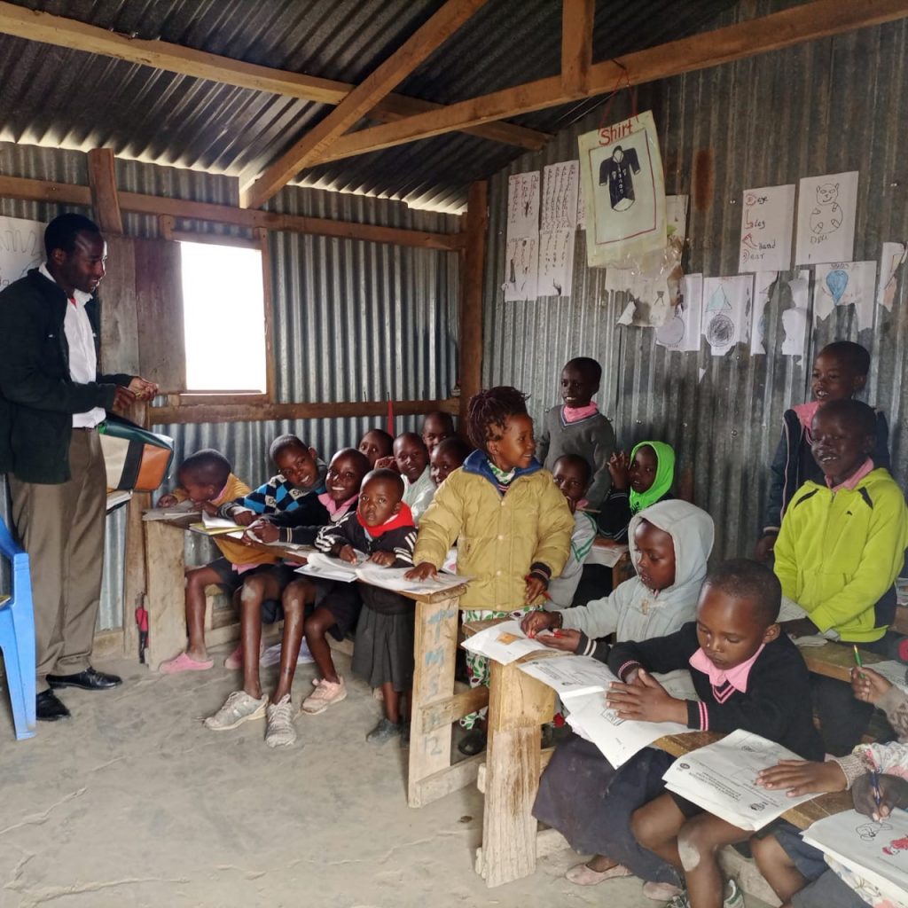 Photograph of head teacher and pupils in basic corrugated iron classroom