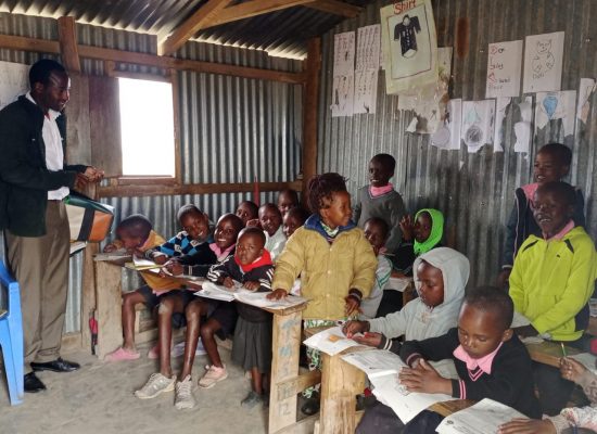 Photograph of head teacher and pupils in basic corrugated iron classroom